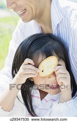 Stock Photography - Daughter Looking Through Biscuit. Fotosearch