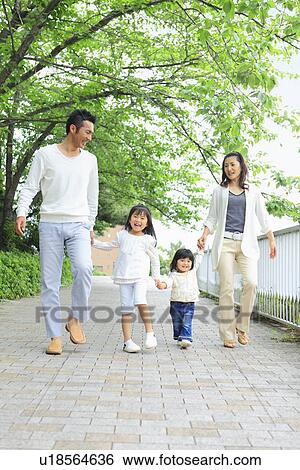 Stock Photograph - Family of Four Holding Hands and Walking in Park. Fotosearch