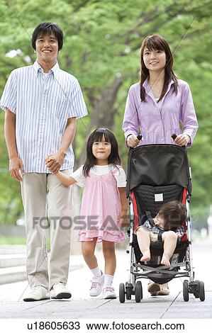 Stock Image - Family of Four Walking in Park. Fotosearch