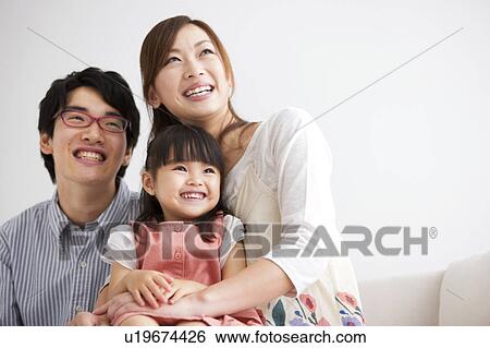 Family sitting on sofa and looking away View Large Photo Image Stock Photograph - Family sitting on sofa and looking away . Fotosearch