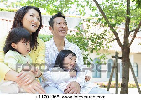 Stock Photography - Family with Two Daughters Sitting Outdoors. Fotosearch