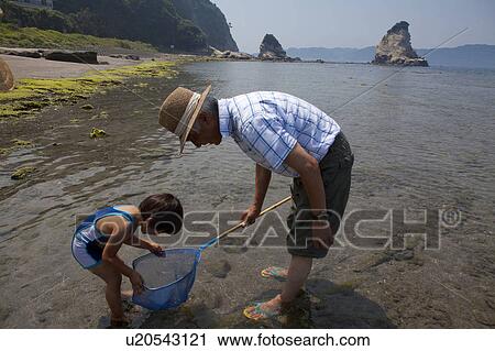 Stock Image - Father and Son with Net at Beach. Fotosearch