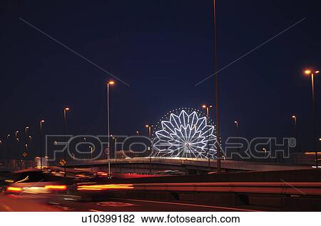 Stock Image - Ferris Wheel and Motorway Illuminated at Night. Fotosearch