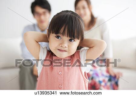 Stock Image - Girl and parents sitting on sofa. Fotosearch