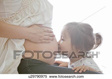 Stock Photography - Girl Kissing Her Pregnant Mother's Belly. Fotosearch