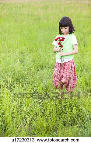 Stock Image - Girl with Bunch of Flowers in Field. Fotosearch
