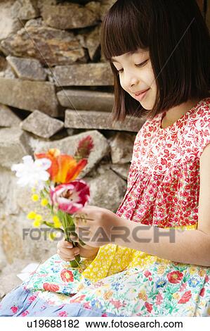 Stock Image - Girl with Flowers Sitting on Windowsill. Fotosearch
