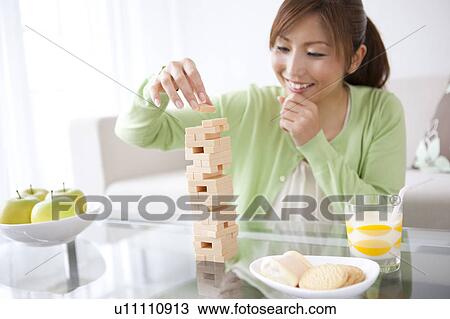 Stock Image - Mid Adult Woman Playing Jenga at Home. Fotosearch