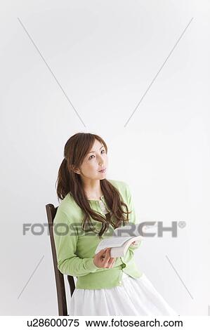 Stock Photography - Mid Adult Woman Reading Book and Looking Up. Fotosearch