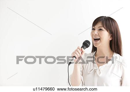 Stock Image - Mid Adult Woman Singing Karaoke. Fotosearch