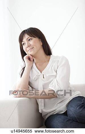Stock Photography - Mid Adult Woman Sitting on Sofa. Fotosearch