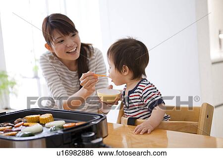 Stock Photograph - Mother Feeding Baby Boy. Fotosearch
