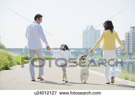 Stock Photo - Parents and Two Daughters Walking at Waterfront. Fotosearch