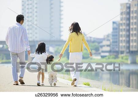 Stock Photograph - Parents and Two Daughters Walking at Waterfront. Fotosearch