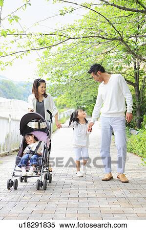 Stock Photography - Parents and Two Daughters Walking in Park. Fotosearch