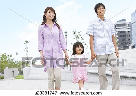 Stock Photo - Parents Walking Hand in Hand with Daughter. Fotosearch