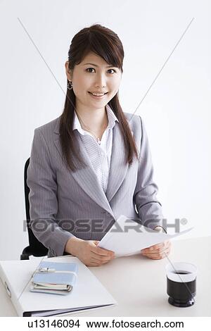 Picture - Portrait of businesswoman sitting at her desk. Fotosearch