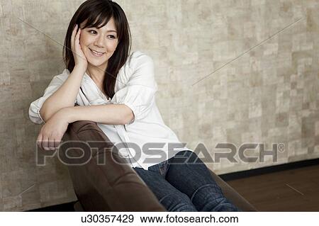 Stock Photo - Portrait of Mid Adult Woman Sitting on Leather Sofa. Fotosearch