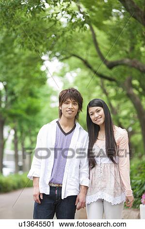 Portrait of young couple standing side by side smiling View Large Photo Image Stock Image - Portrait of young couple standing side by side smiling. Fotosearch