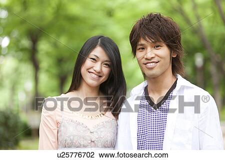 Portrait of young couple standing side by side smiling View Large Photo Image Stock Image - Portrait of young couple standing side by side smiling. Fotosearch
