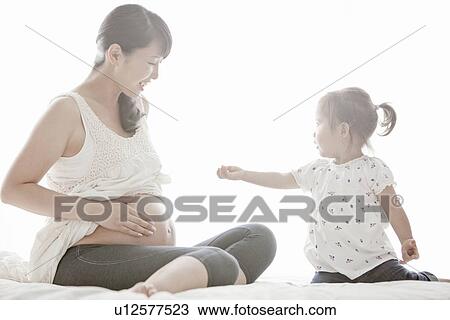 Stock Image - Pregnant Mother and Her Young Daughter. Fotosearch
