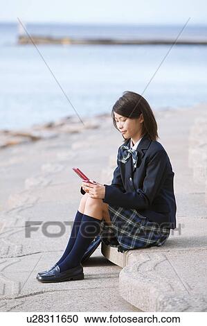 Stock Image - School Girl Using Mobile Phone at Beach. Fotosearch
