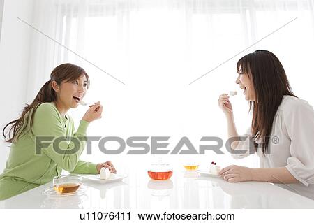 Stock Image - Two Female Friends Eating Cake. Fotosearch