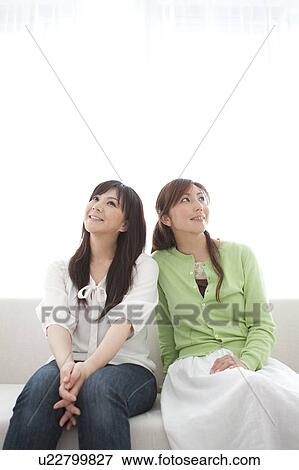 Two Mid adult Women Sitting on Sofa and Looking Up View Large Photo Image Stock Photo - Two Mid adult Women Sitting on Sofa and Looking Up. Fotosearch