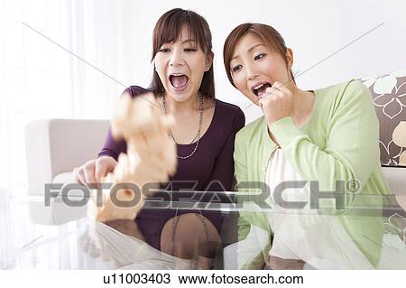 Stock Image - Two Women Watching Jenga Tower to Fall. Fotosearch