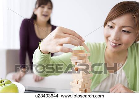 Woman Playing Jenga, Friend in Background View Large Photo Image Picture - Woman Playing Jenga, Friend in Background. Fotosearch