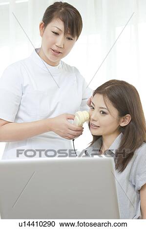 Stock Image - Women looking at details of facial skin on computer. Fotosearch