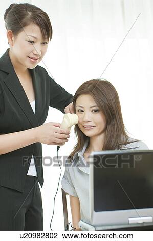 Stock Image - Women looking at details of facial skin on computer. Fotosearch