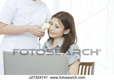 Stock Image - Women looking at details of facial skin on computer. Fotosearch