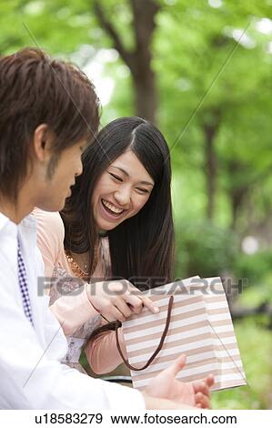 Stock Photo - Young couple looking inside a shopping bag. Fotosearch
