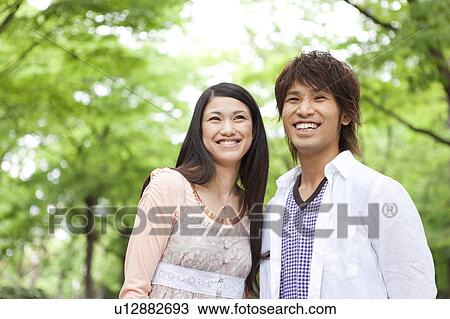 Young couple standing side by side smiling View Large Photo Image Stock Image - Young couple standing side by side smiling. Fotosearch