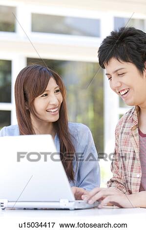 Stock Photo - Young Couple Using Laptop Outdoors. Fotosearch