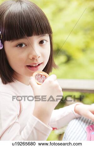 Stock Image - Young Girl Eating Biscuit. Fotosearch