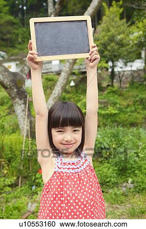 Stock Image - Young Girl Holding Black Board Aloft. Fotosearch