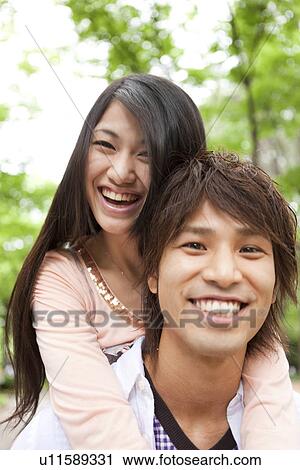 Stock Image - Young man giving girlfriend piggyback. Fotosearch