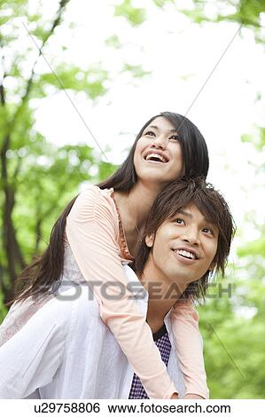 Stock Photograph - Young man giving girlfriend piggyback. Fotosearch