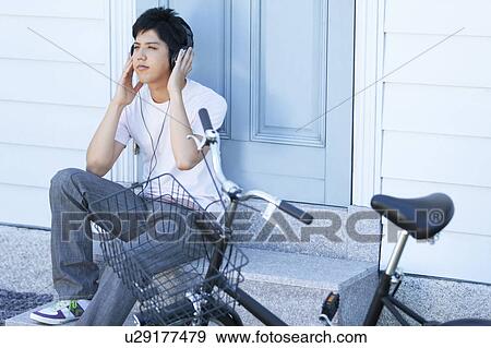 Stock Photo - Young Man Listening to Headphones on Steps. Fotosearch
