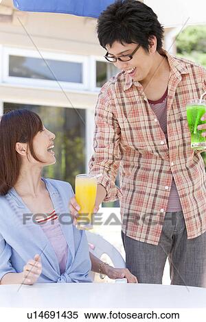 Stock Photography - Young Man Serving Juice to Girlfriend. Fotosearch