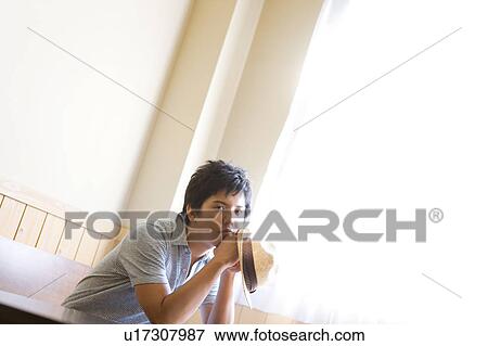 Stock Photo - Young Man Sitting at Wooden Table. Fotosearch