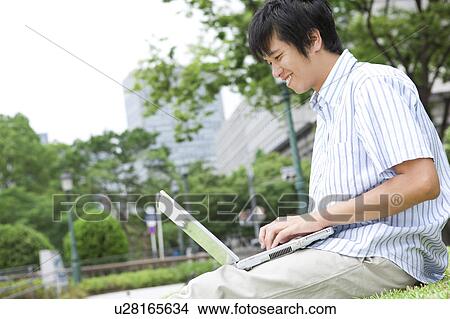 Young Man Using Laptop in Park View Large Photo Image Picture - Young Man Using Laptop in Park. Fotosearch