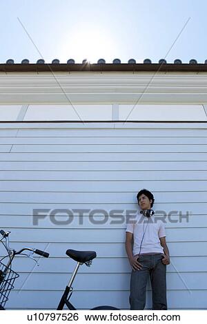 Stock Photograph - Young Man with Bicycle Leaning on Wall. Fotosearch