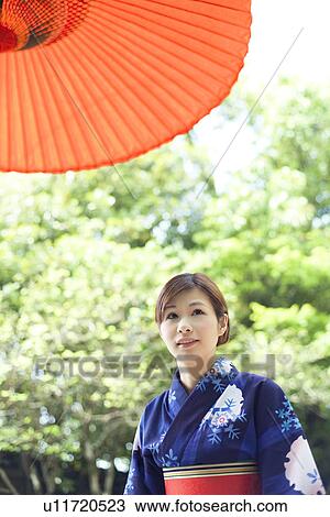 Stock Image - Young Woman Below Umbrella. Fotosearch