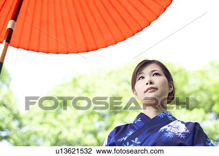 Stock Image - Young Woman Below Umbrella. Fotosearch