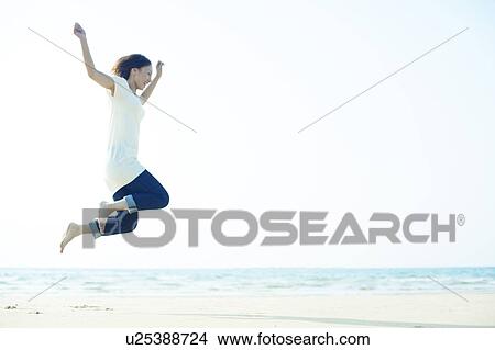 Young Woman Jumping on Beach View Large Photo Image Picture - Young Woman Jumping on Beach. Fotosearch