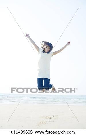 Stock Image - Young Woman Jumping on Beach. Fotosearch