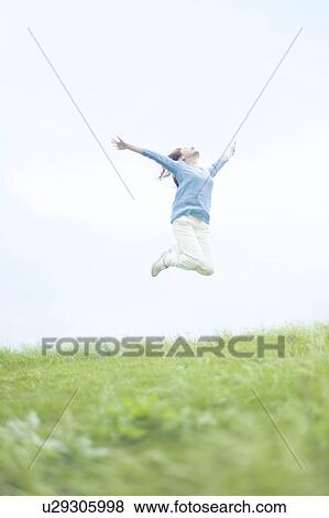 Stock Photo - Young Woman Jumping on Grass. Fotosearch